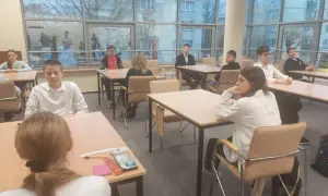 Uczniowie podczas mscdn konkursy przedmiotowe. Młodzi ludzie siedzą przy stołach, skupieni na zadaniach.