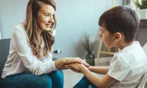 Kobieta wspiera chłopca, trzymając go za ręce. Orzeczenie o zagrożeniu niedostosowaniem społecznym może pomóc w uzyskaniu wsparcia.