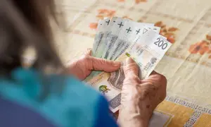 Dłonie starszej osoby liczą polskie banknoty 200 zł.