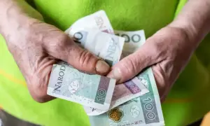 Dłonie trzymają polskie banknoty. Nowe zasady przyznawania renty socjalnej mogą wpłynąć na finanse wielu osób.