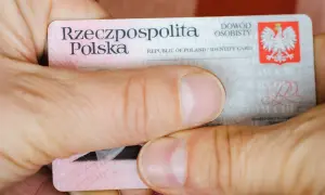 Dłonie trzymają polski dowód osobisty. Widoczna jest nazwa "Rzeczpospolita Polska" oraz godło. Widać fragmenty tekstu, w tym "seria i numer dowodu".