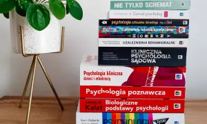 Stos książek o psychologii, w tym psychologia kliniczna, obok rośliny w doniczce.