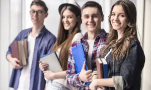 Uśmiechnięci młodzi ludzie z książkami i teczkami. Czy szkoła policealna daje status studenta?