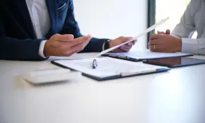 Dwóch mężczyzn omawia dokumenty, być może umowę o pracę zgodną z art. 52 kodeksu pracy.