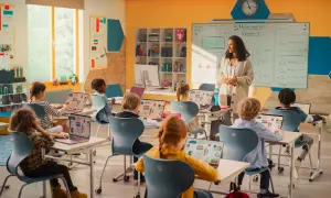Nauczycielka prowadzi lekcję matematyki w nowoczesnej klasie. Dzieci uczą się z laptopów, co pokazuje postęp w pracy w oświacie.
