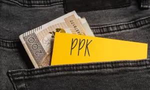 Żółta kartka z napisem "ppk" wystaje z kieszeni dżinsów obok banknotów. Decyzja o rezygnacji z PPK.