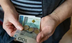 Dłonie trzymają polskie banknoty i monety. Nadzieja na waloryzację rent i emerytur 2026.