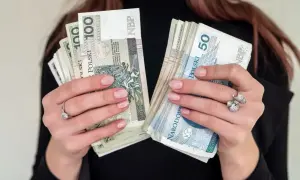Dłonie trzymające pliki polskich banknotów 100 i 50 zł. Zastanawiasz się, jaka emerytura przy zarobkach 7000 brutto?