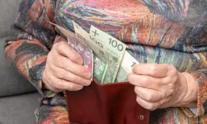 Dłonie starszej osoby wkładają polskie banknoty do portfela. Zastanawiasz się, o ile wzrośnie emerytura po roku pracy na emeryturze?
