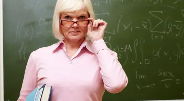 Nauczycielka matematyki z okularami i książkami, myśląca o emeryturach dla nauczycieli.