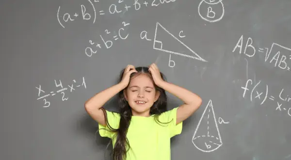 Dziewczynka z rękami wplątanymi we włosy, wyraźnie przeżywająca problemy z matematyką. Wokół niej wzory i figury geometryczne na tablicy.