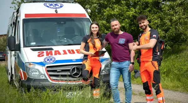 Trzech ratowników medycznych przy ambulansie. Zastanawiasz się, ile zarabia ratownik medyczny?