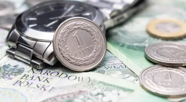 Zegarek i monety na banknotach. Czy to symbol najniższa krajowa na godzinę?
