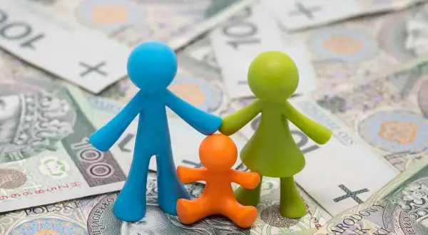 Figurki symbolizujące rodzinne szczęście na tle polskich banknotów.