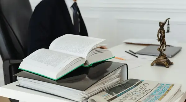 Prawnik w garniturze studiuje prawo, obok otwarty kodeks, akta i Dziennik Gazeta Prawna. Czas na vacatio legis.