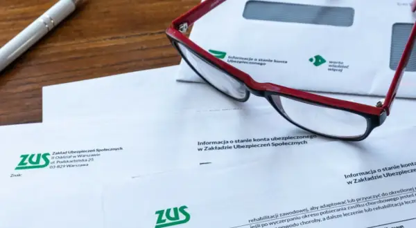 Okulary leżą na dokumentach ZUS, wśród których znajduje się wniosek o świadczenie rehabilitacyjne.