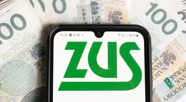Telefon z logo ZUS na tle polskich banknotów 100 zł.