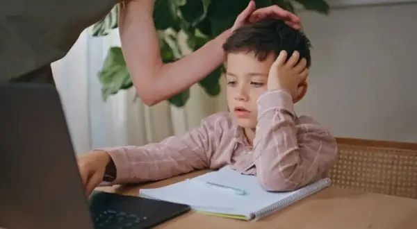 Chłopiec z rezygnacją opiera głowę na dłoni, wyraźnie widać, że dziecko nie chce się uczyć.
