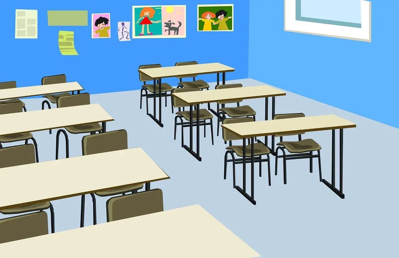 Pusta klasa z rzędami pustych stołów i krzeseł, na ścianie rysunki dzieci.