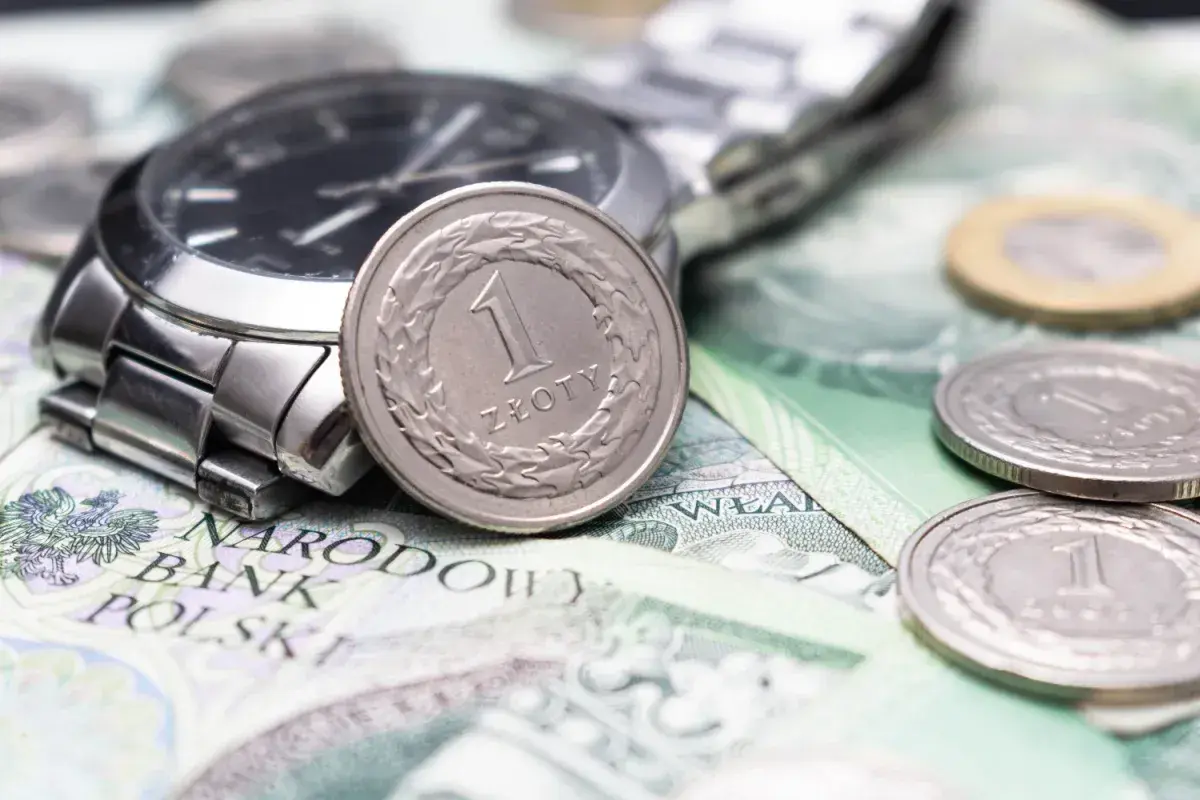 Zegarek i monety na banknotach. Czy to symbol najniższa krajowa na godzinę?