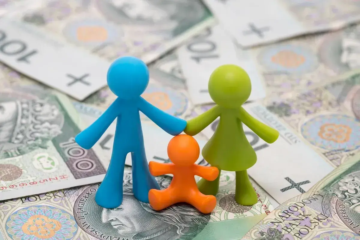 Figurki symbolizujące rodzinne szczęście na tle polskich banknotów.