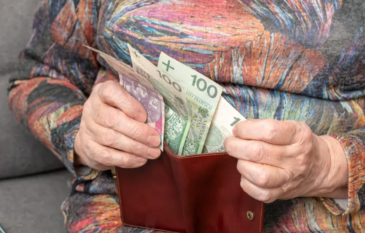 Dłonie starszej osoby wkładają polskie banknoty do portfela. Zastanawiasz się, o ile wzrośnie emerytura po roku pracy na emeryturze?