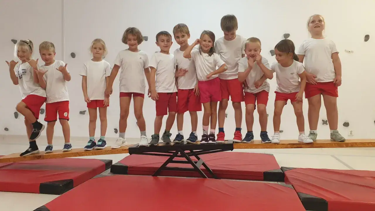 Dzieci w strojach sportowych ćwiczą na sali gimnastycznej. Wychowanie fizyczne w szkołach to świetna zabawa i rozwój.