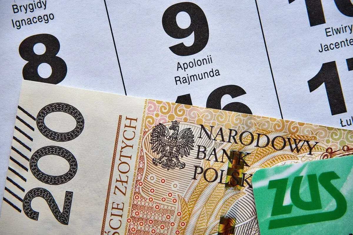 Kalendarz z datami i nazwami, banknot 200 zł i zielona karta ZUS. Od czego zależy termin wypłaty emerytury?
