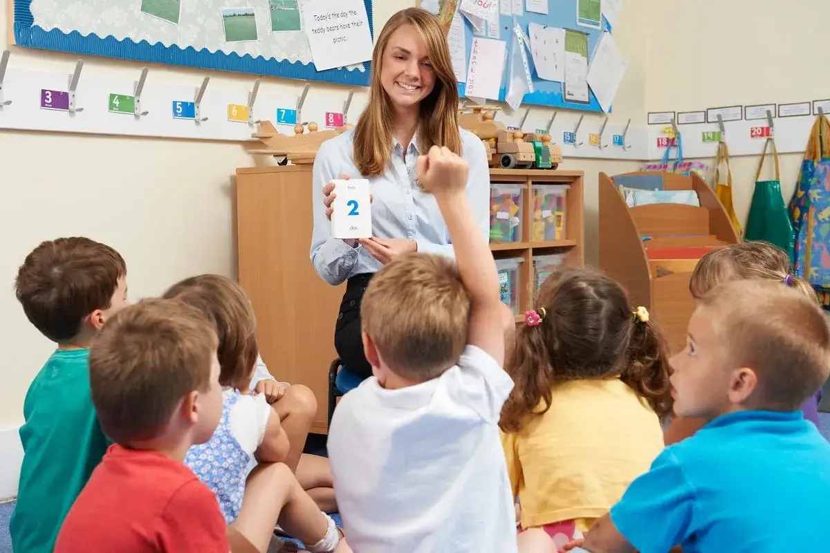 Nauczycielka pokazuje dzieciom kartę z cyfrą 2. Wesoła praca w przedszkolu, gdzie nauka jest zabawą.