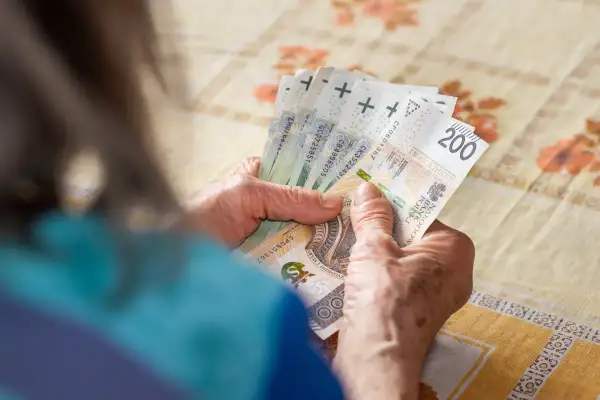 Dłonie starszej osoby liczą polskie banknoty 200 zł.
