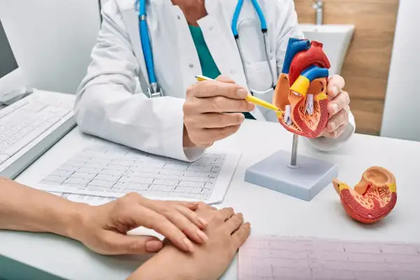Lekarz omawia z pacjentem model serca i EKG, wyjaśniając ścieżkę rehabilitacyjną.