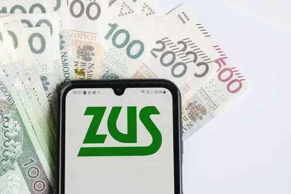 Telefon z logo ZUS na tle polskich banknotów. Termin wypłaty emerytury zależy od wielu czynników, w tym od prawidłowego zgłoszenia i przetwarzania wniosku.