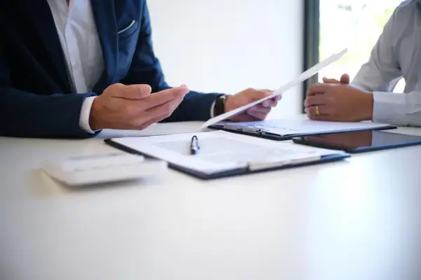 Dwóch mężczyzn omawia dokumenty, być może umowę o pracę zgodną z art. 52 kodeksu pracy.