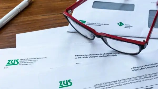 Okulary leżą na dokumentach ZUS, wśród których znajduje się wniosek o świadczenie rehabilitacyjne.