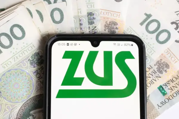Telefon z logo ZUS na tle polskich banknotów 100 zł.